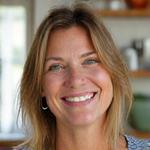 Smiling woman in her 40s, Sarah, enjoying a healthy breakfast in a well-lit kitchen.